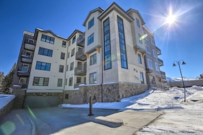 A multi-story residential building with a stone facade, large windows, and balconies. - Hike & Bike! Mtn-view Condo 1 Block to Main St (Winter Park)
