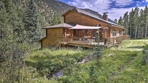 A log cabin with a deck and outdoor seating area, surrounded by forest and mountains. - Silver Plume Mountain Haven With Views & Deck! (Silver Plume)