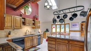 A kitchen with wooden cabinets, a granite countertop, a dishwasher, and a hanging pot rack. - Silver Plume Mountain Haven With Views & Deck! (Silver Plume)