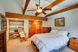 A bedroom with a large bed, wooden ceiling beams, a ceiling fan, a bookshelf, a rocking chair, and a dresser. - Silver Plume Mountain Haven With Views & Deck! (Silver Plume)