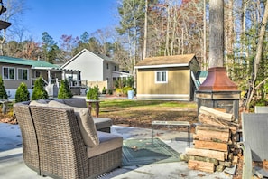 A patio area with wicker furniture, a fire pit, and a stack of firewood. - 9 Mi to Ocean City Beaches: Retreat w/ Patio (Berlin)