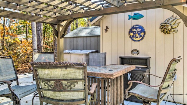 An outdoor patio with a wooden pergola, a table, and chairs. There is a sign on the wall that reads "John's Tiki Bar."