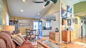 A spacious living room with a large brown sofa, a glass-top coffee table, and a dining area with chairs and a table.