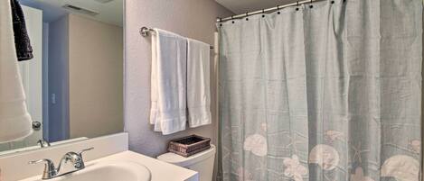 A bathroom with a white sink, a mirror, a toilet, and a shower curtain with a floral pattern.