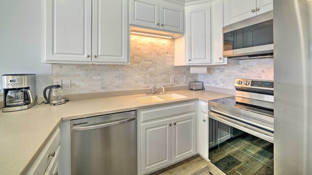 A modern kitchen with white cabinetry, a built-in oven, and a stainless steel refrigerator. - Sunny PCB Home w/ Balcony: Steps to the Beach! (Panama City Beach)