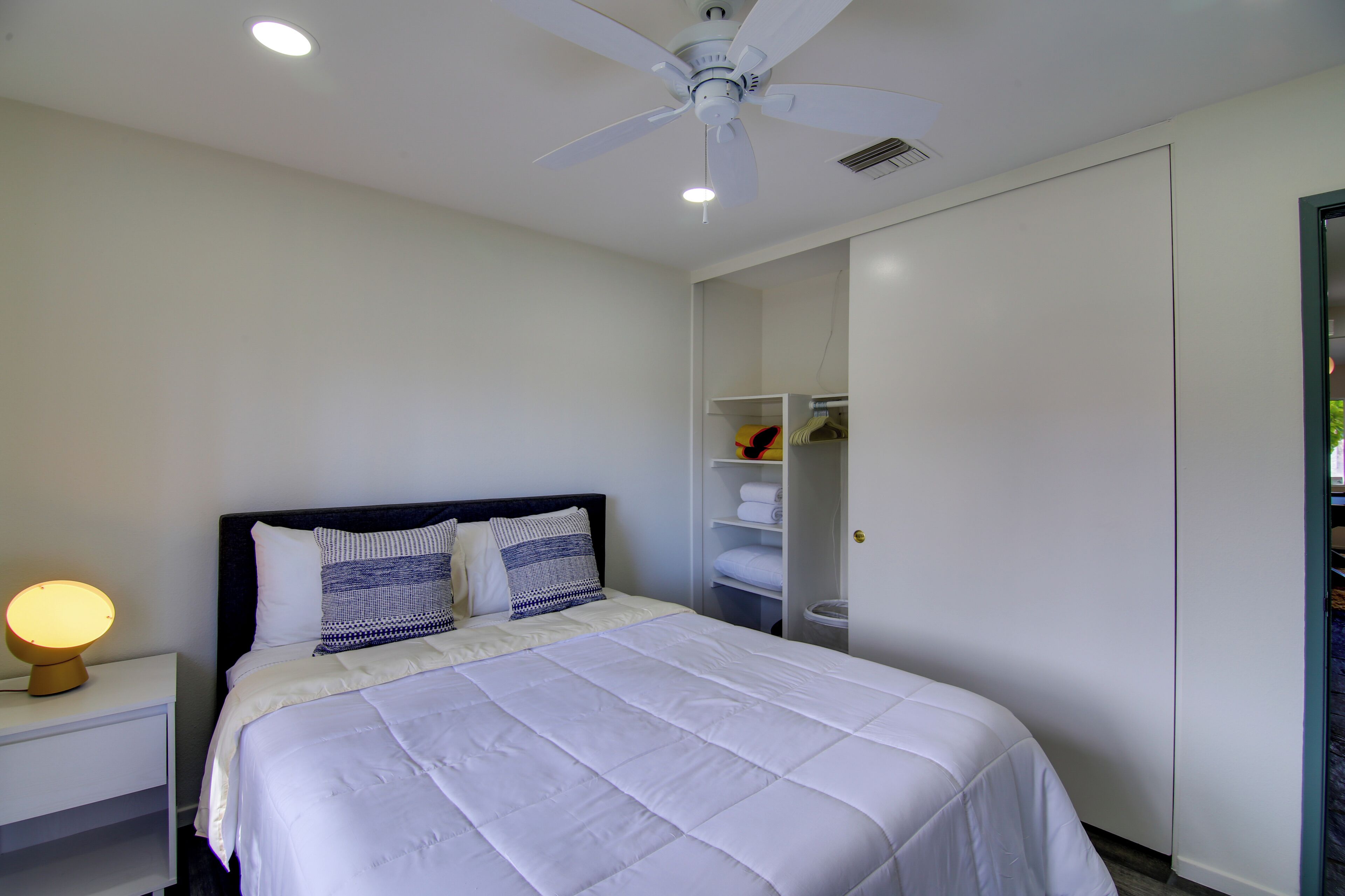 A bedroom with a bed, bedside table, and a wardrobe.