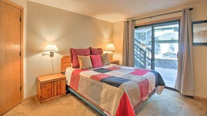 Een slaapkamer met een bed, twee bedlampen, een nachtkastje en uitzicht buiten via een schuifdeur.