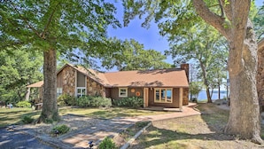 A stone building with a brown roof, surrounded by trees and a clear sky. - Grand Lake Views + Fire Pit: Monkey Island Home! (Afton)
