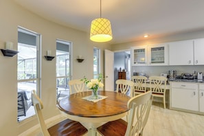 A dining area with a wooden table, white chairs, a vase of flowers, and a hanging light fixture. - 3 Mi to Dunnellon Historic District: Home w/ Lanai (Citrus Springs)