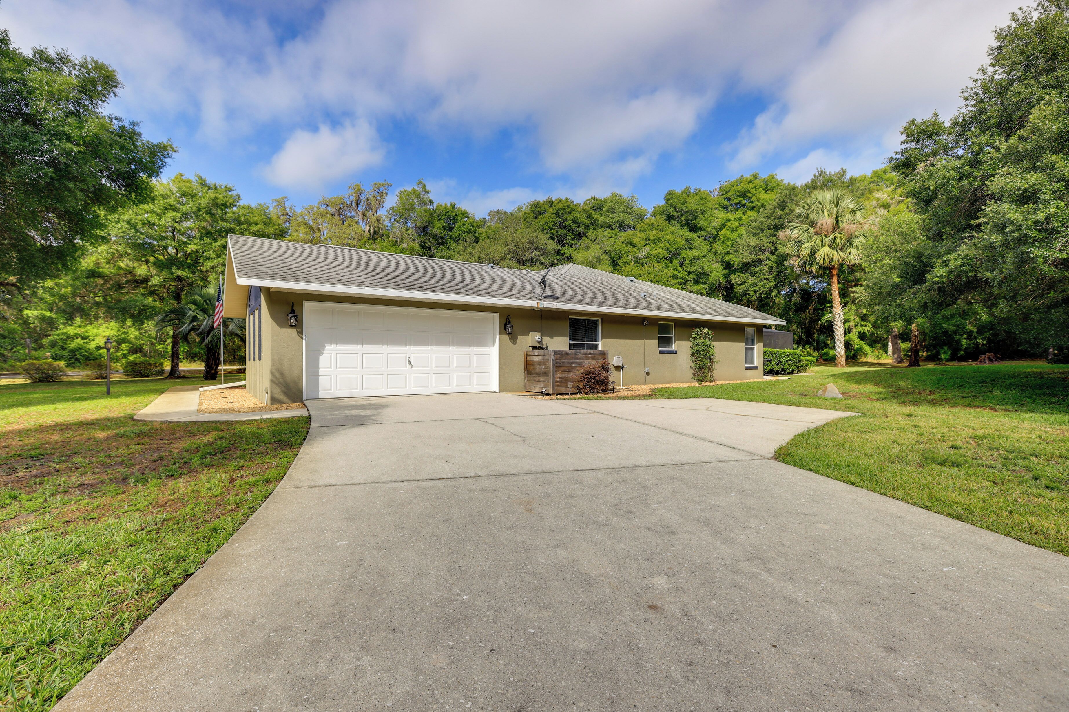 A single-story house with a garage, surrounded by a well-maintained lawn and trees.