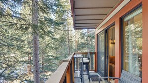 Un balcon doté d'une balustrade en bois, de deux fauteuils en osier et d'une porte vitrée donnant sur un espace intérieur.