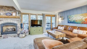Un salon chaleureux avec une cheminée en pierre, un téléviseur, un canapé en cuir et un tableau accroché au mur.