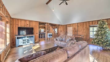 A spacious living room with a large sectional sofa, a television, and a Christmas tree.