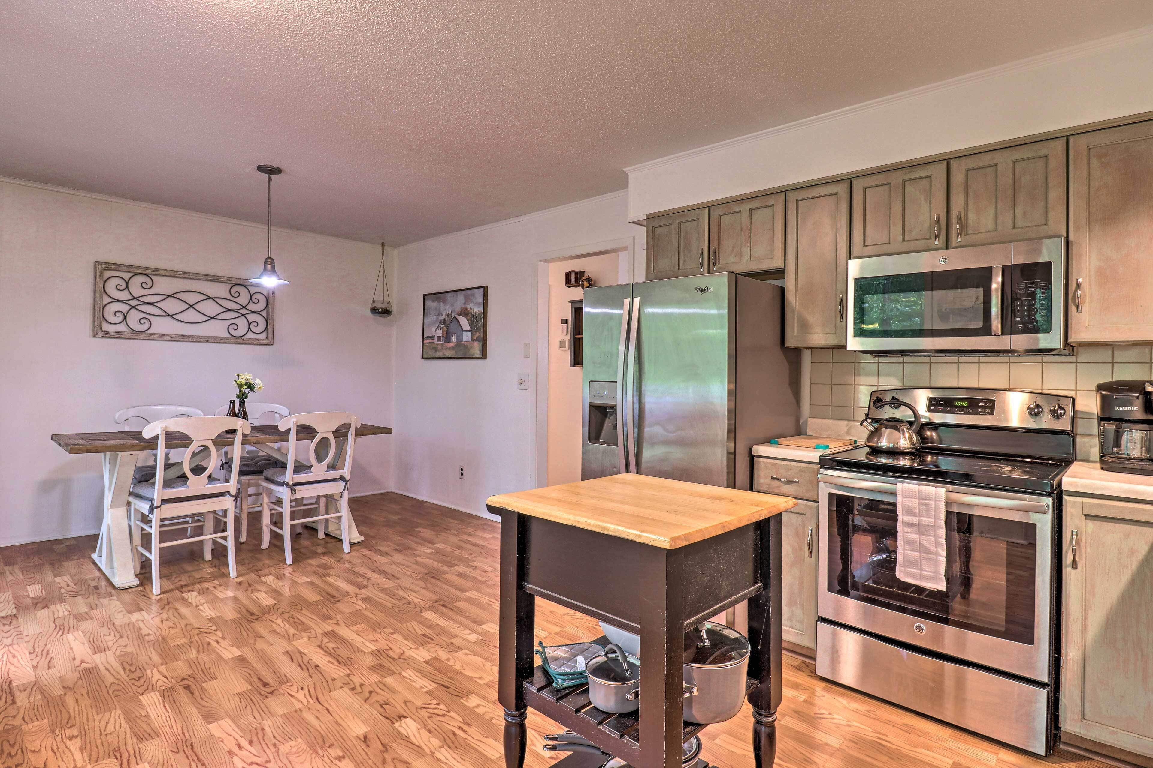 A kitchen with wooden cabinets, a refrigerator, a microwave, an oven, and a dining table with chairs.