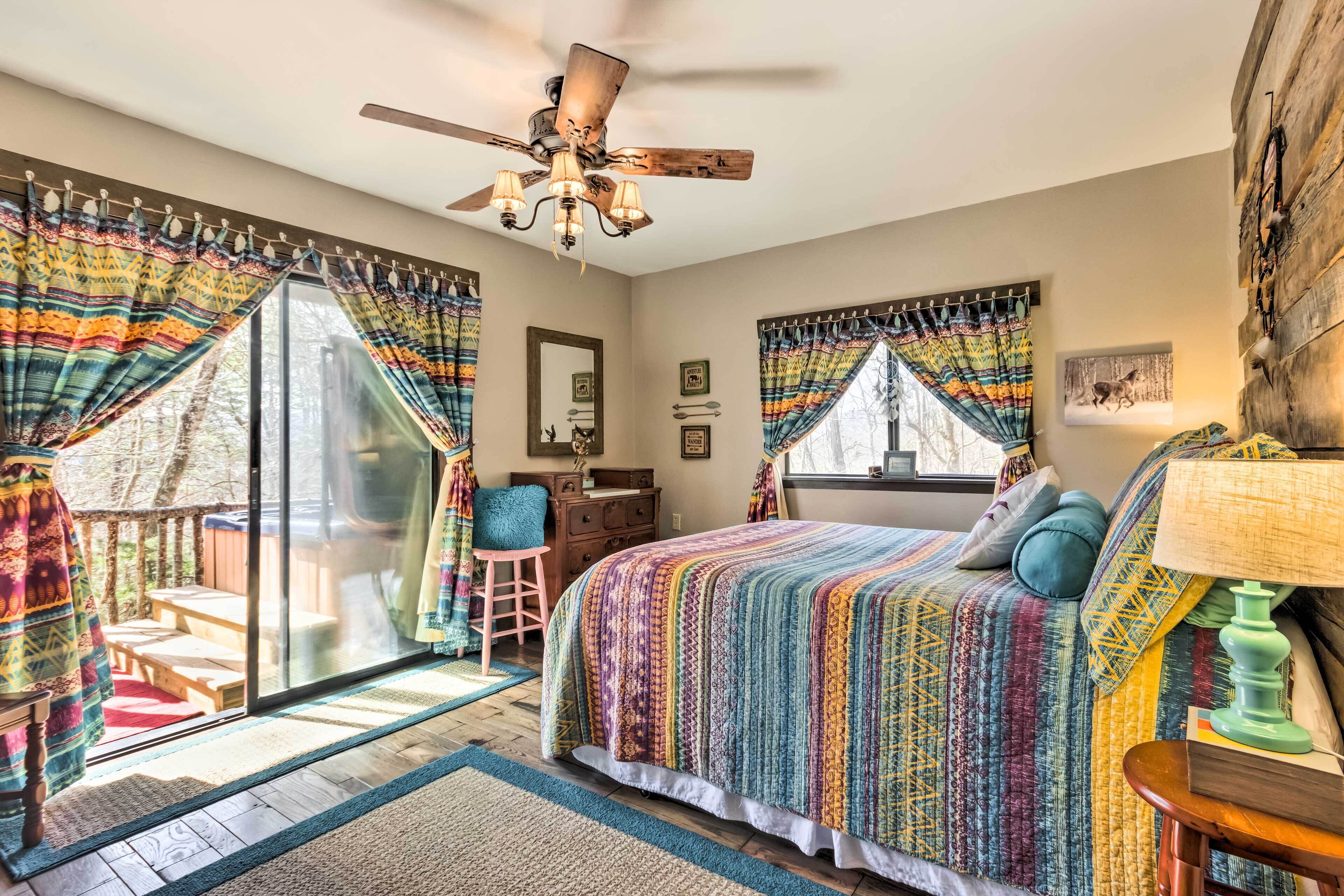 A bedroom with a large bed, a ceiling fan, and a view of the outdoors.