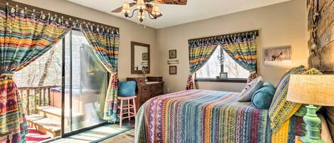 A bedroom with a large bed, a ceiling fan, and a view of the outdoors.