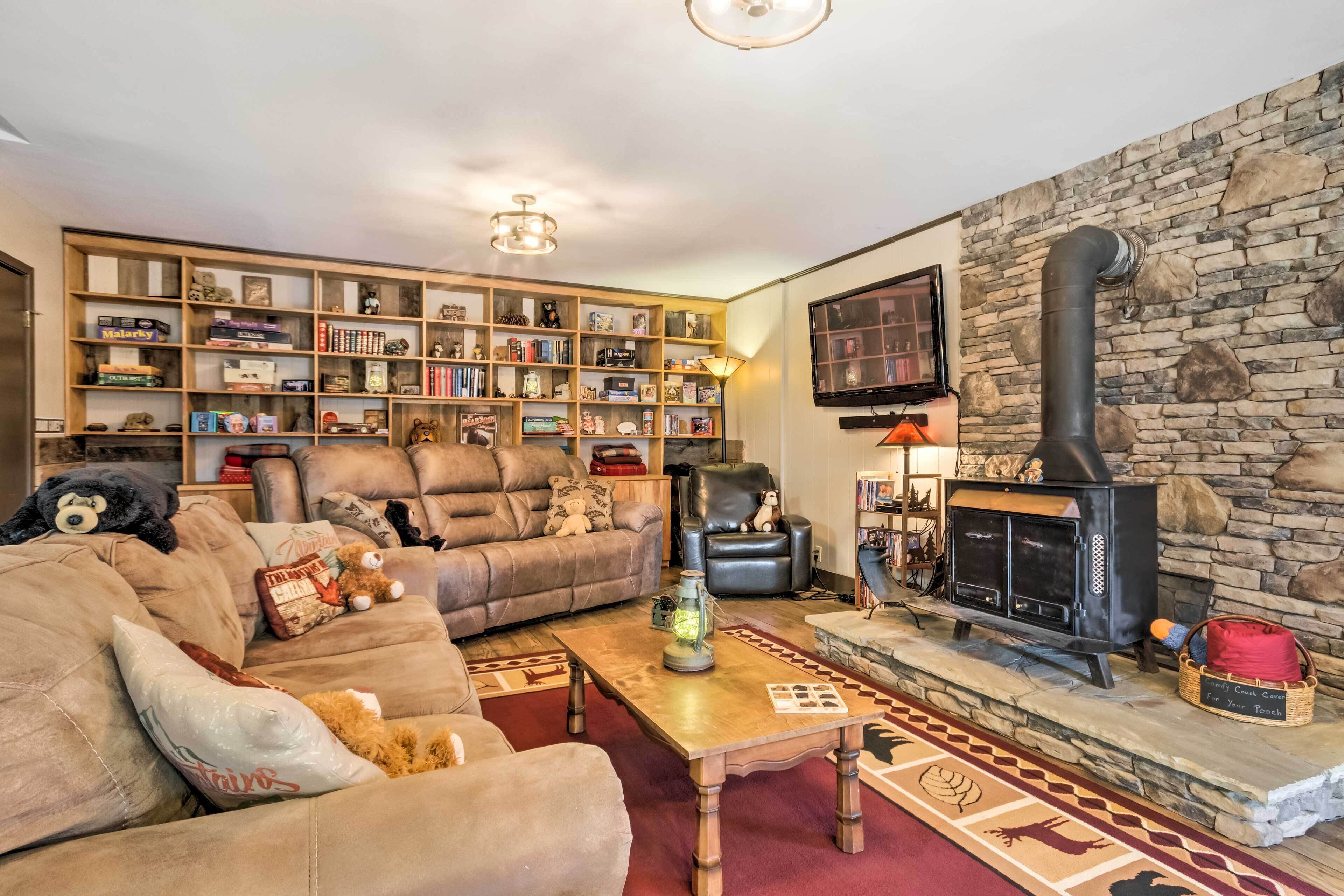 Una sala de estar acogedora con chimenea, sofás de cuero, una estantería y un televisor montado en la pared.