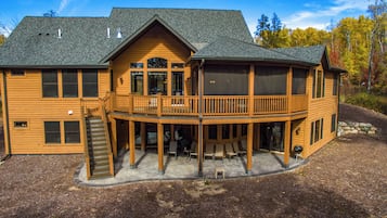 A two-story wooden house with a balcony and a covered patio area.