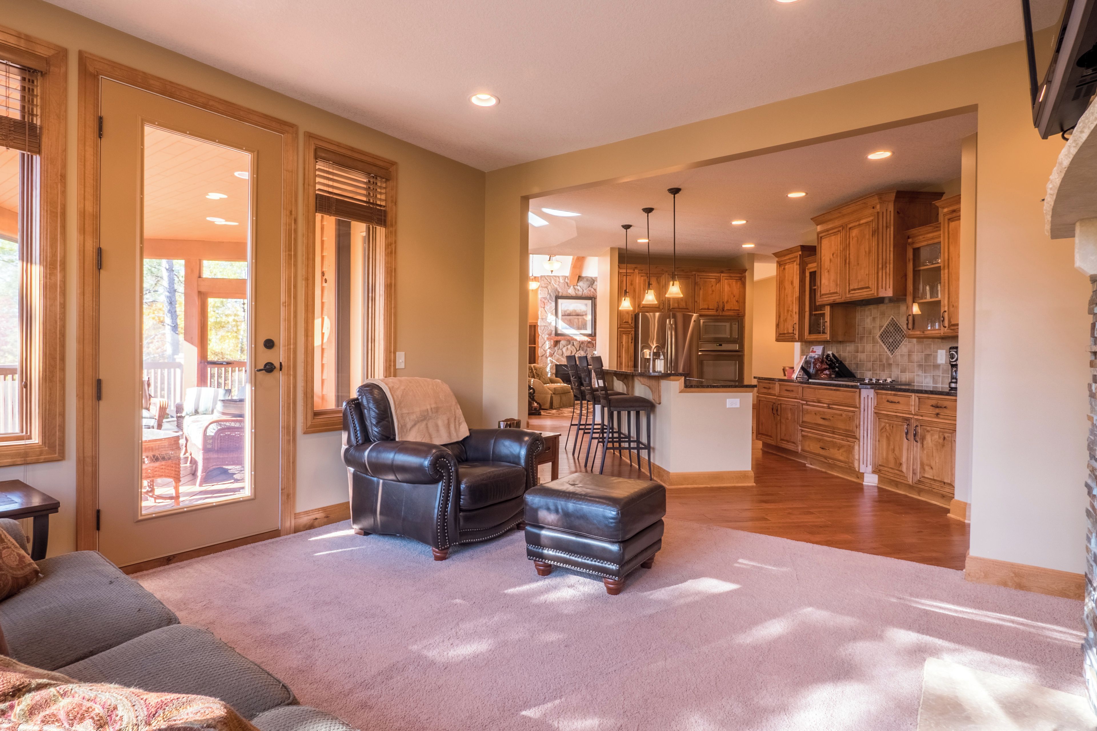 A spacious living area with a leather sofa, ottoman, and a dining area with bar stools.