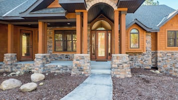A modern house with a stone facade, a central entrance with a glass door, and a stone pathway leading to the front door.