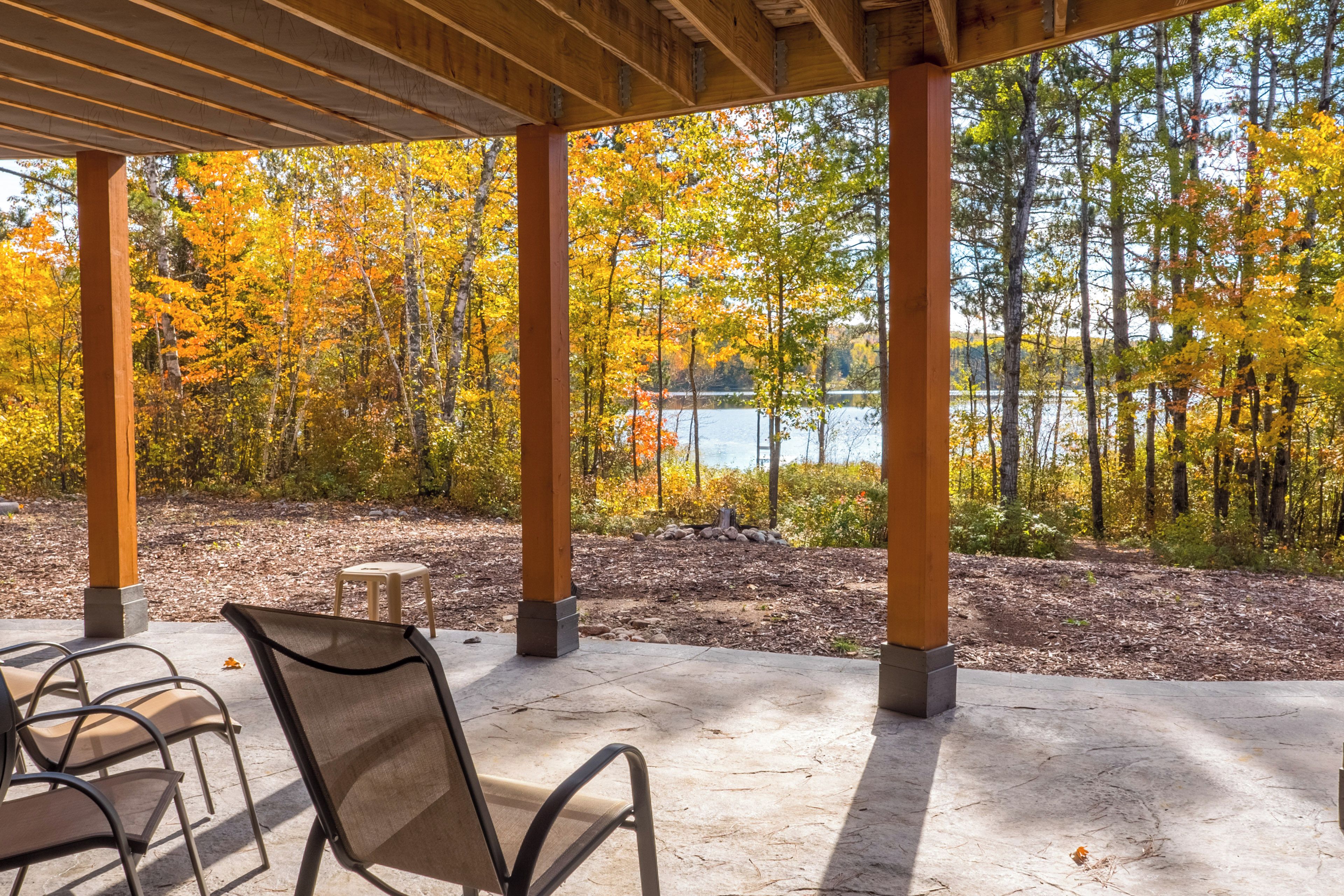 An outdoor seating area with a view of a lake surrounded by trees in autumn colors.