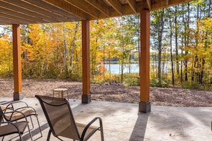 An outdoor seating area with a view of a lake surrounded by trees in autumn colors. - Lakefront Retreat at Giants Ridge: Golf, Hike, Ski (Aurora)