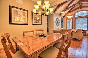 Enjoy meals in this spacious dining area with a large table and comfortable seating for six, surrounded by artwork and natural light.