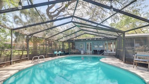 A covered swimming pool with a metal roof, surrounded by lounge chairs and a small building with windows. - Beach Retreat in Jacksonville: Pet/family-friendly (Jacksonville Beach)