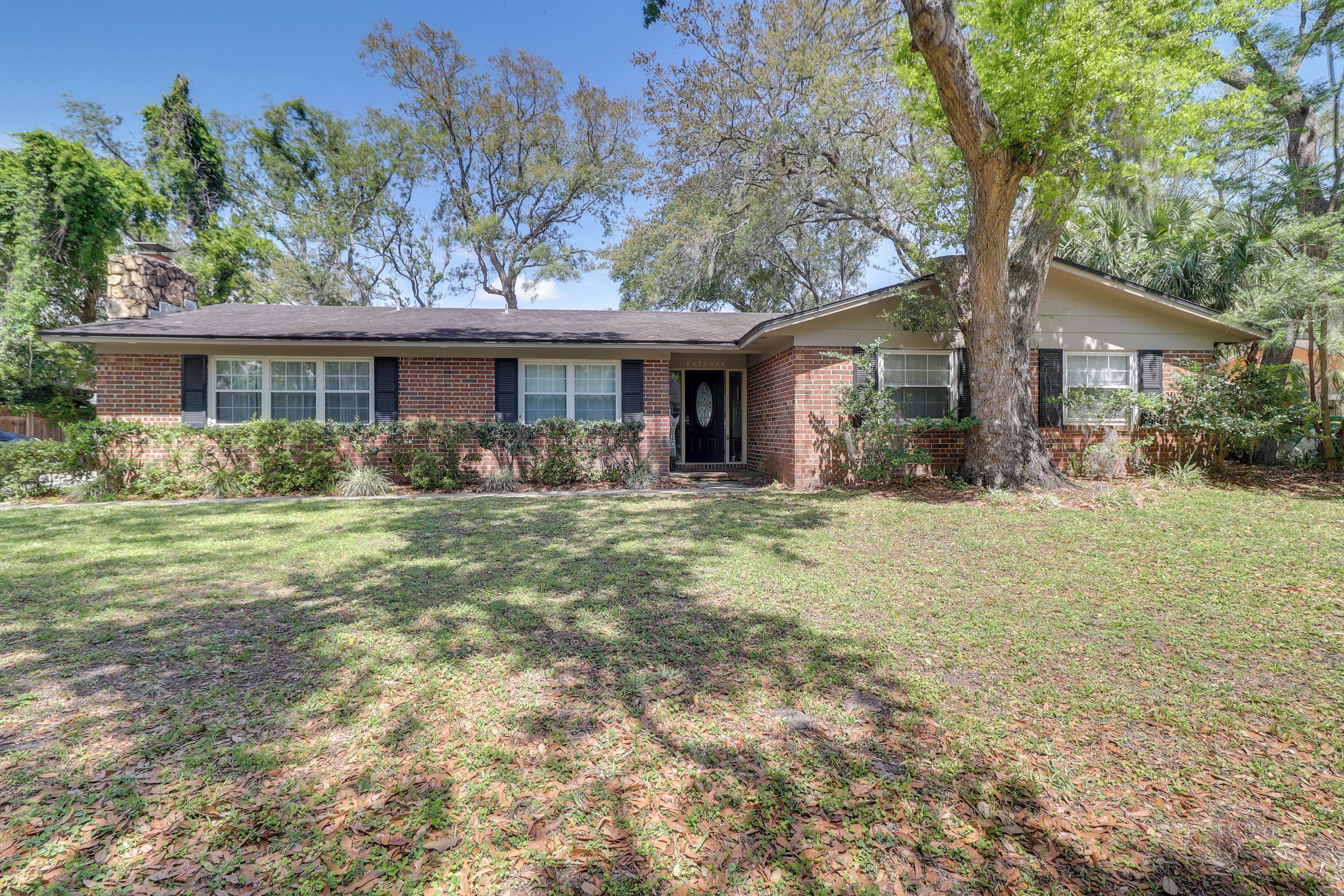 A two-story brick house with a front porch, a garage, and a well-maintained lawn.