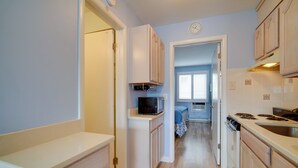 A narrow kitchen with white cabinets, a microwave, a stove, and a sink. - First-floor Brigantine Condo: Steps to Ocean! (Brigantine)