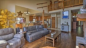 A spacious living room with a leather sectional sofa, a wooden coffee table, and a dining area with a chandelier. - Golf, Ski & Hike: Luxe Group Getaway in Granby! (Granby)