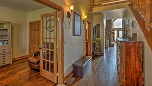 A wooden-floored hallway with a bench, a door with glass panels, and a staircase with a fur-covered handrail. - Golf, Ski & Hike: Luxe Group Getaway in Granby! (Granby)