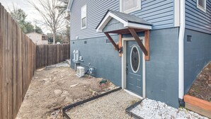 A house with a blue exterior, a wooden deck, and a gravel driveway.