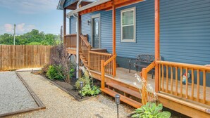 A blue house with a wooden deck, a front door, and a staircase leading to the porch.