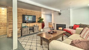 A modern living room with a fireplace, wooden walls, a television, and a sofa. - Snowy Cabin: Generator, Firewood & HWY 108 (Strawberry)