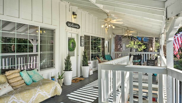 A covered porch with a white railing, a sofa with patterned cushions, and a 'Welcome' sign. - Snowy Cabin: Generator, Firewood & HWY 108 (Strawberry)