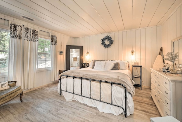Quarto com cama, cômoda e vista para o exterior.