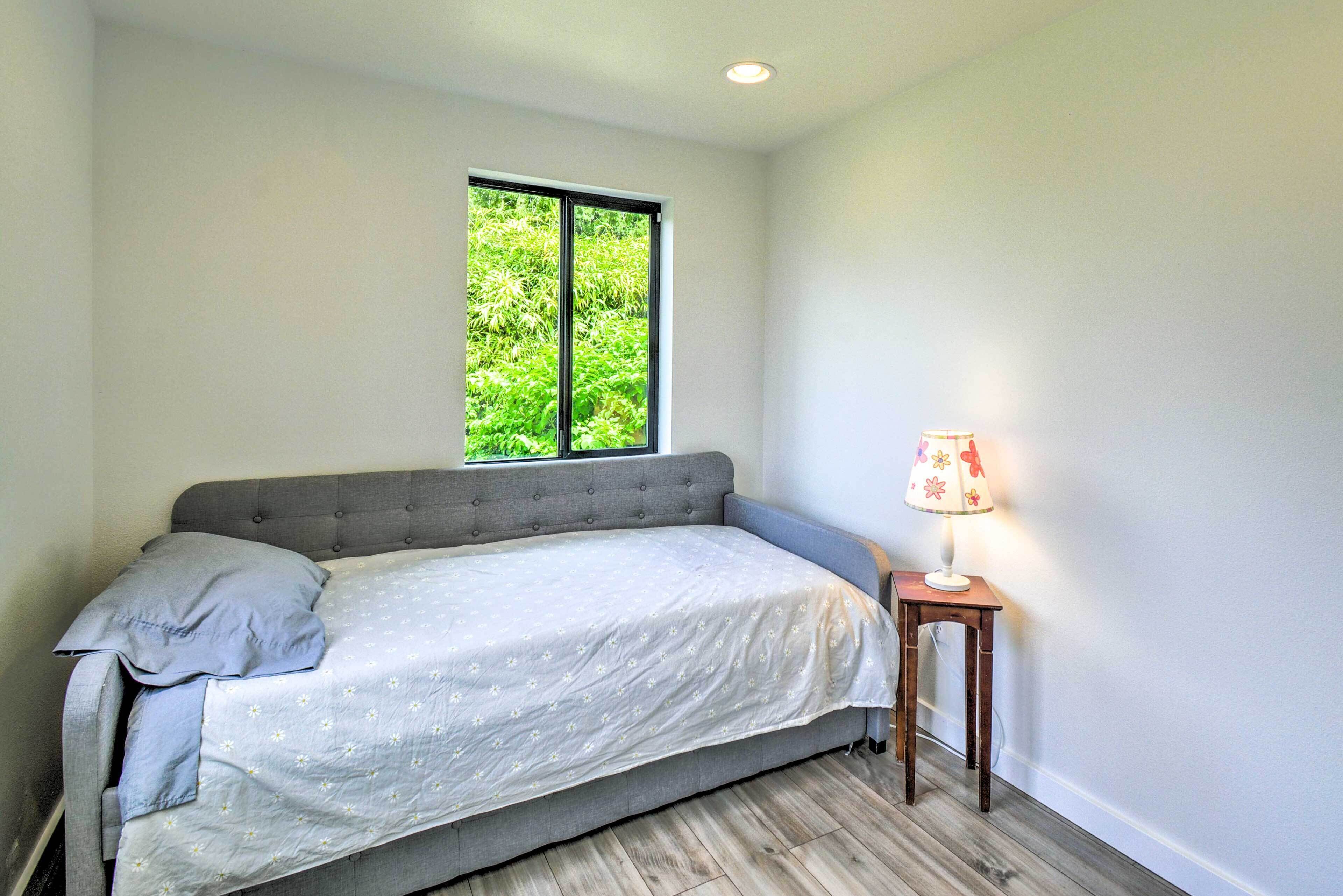 A bedroom with a bed, a window, and a nightstand with a lamp.