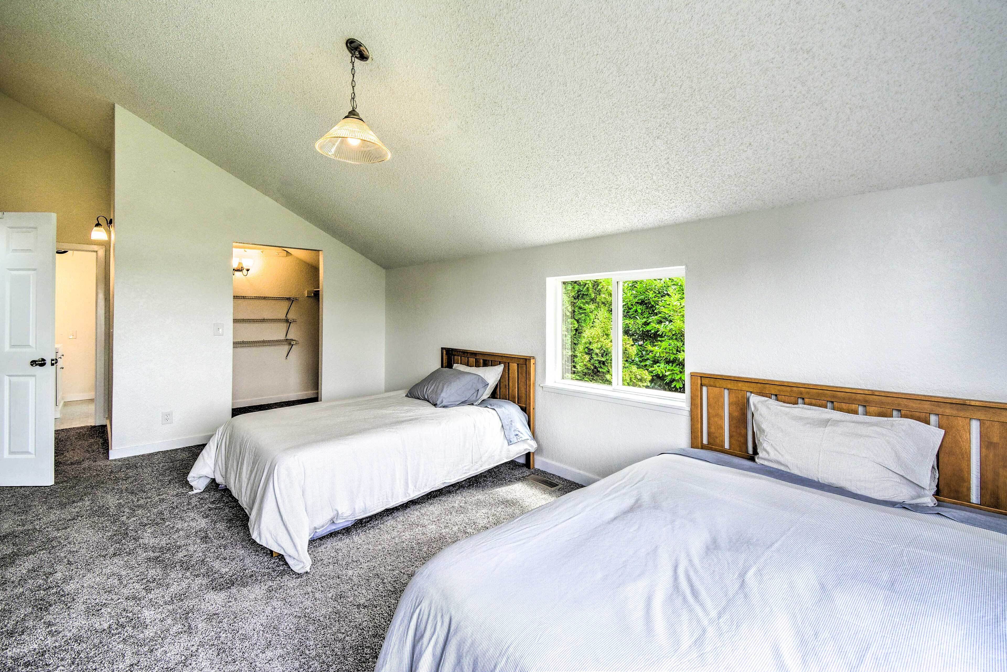 A bedroom with two beds, a window, and a door leading to a bathroom.