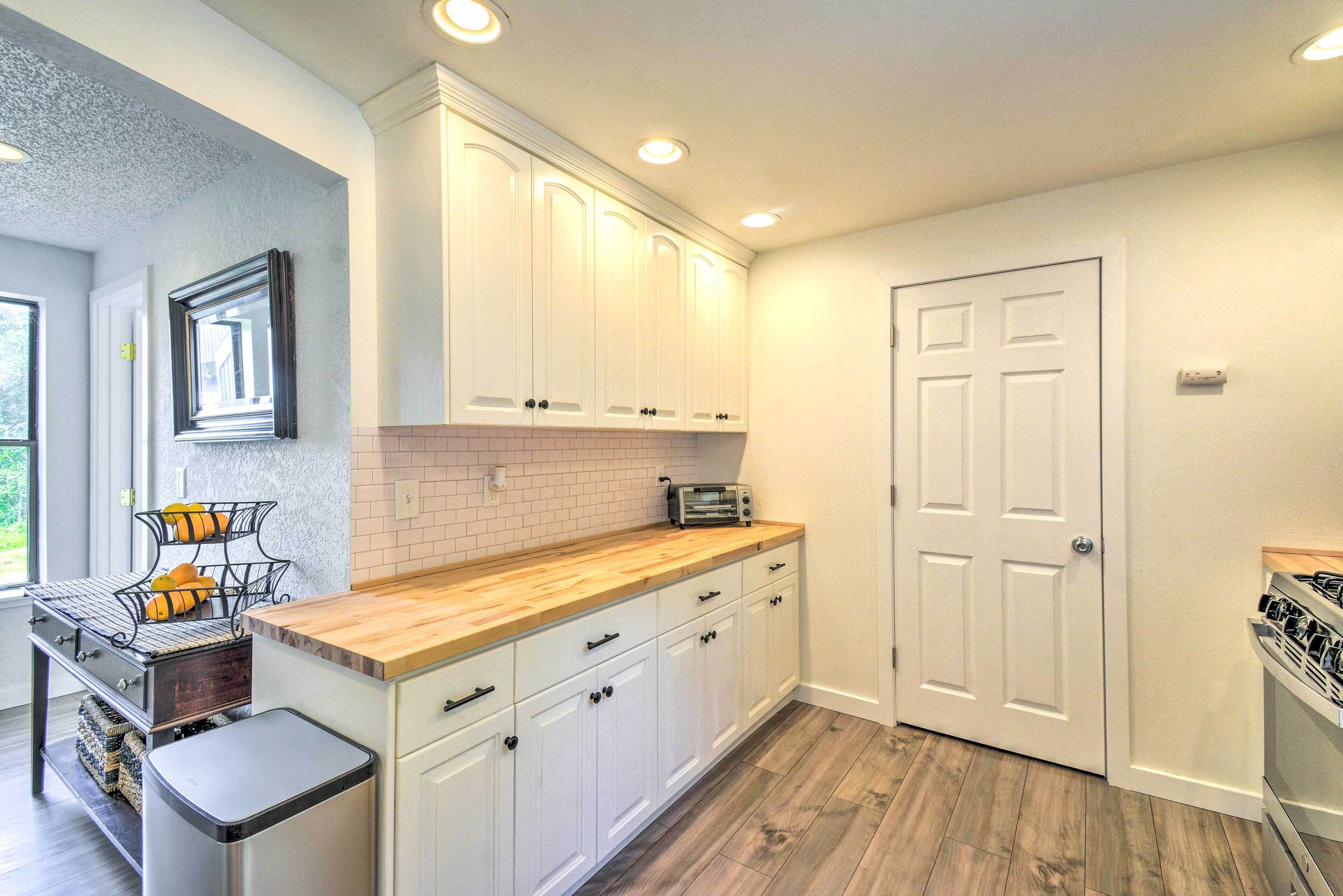A kitchen with white cabinets, a wooden countertop, a built-in oven, and a window.