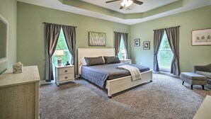 Une chambre à coucher comprenant un lit, des tables de chevet, une commode, une chaise et un ventilateur de plafond.