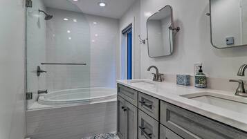 A modern bathroom with a glass-enclosed shower, a freestanding bathtub, and a vanity with a sink and mirror.