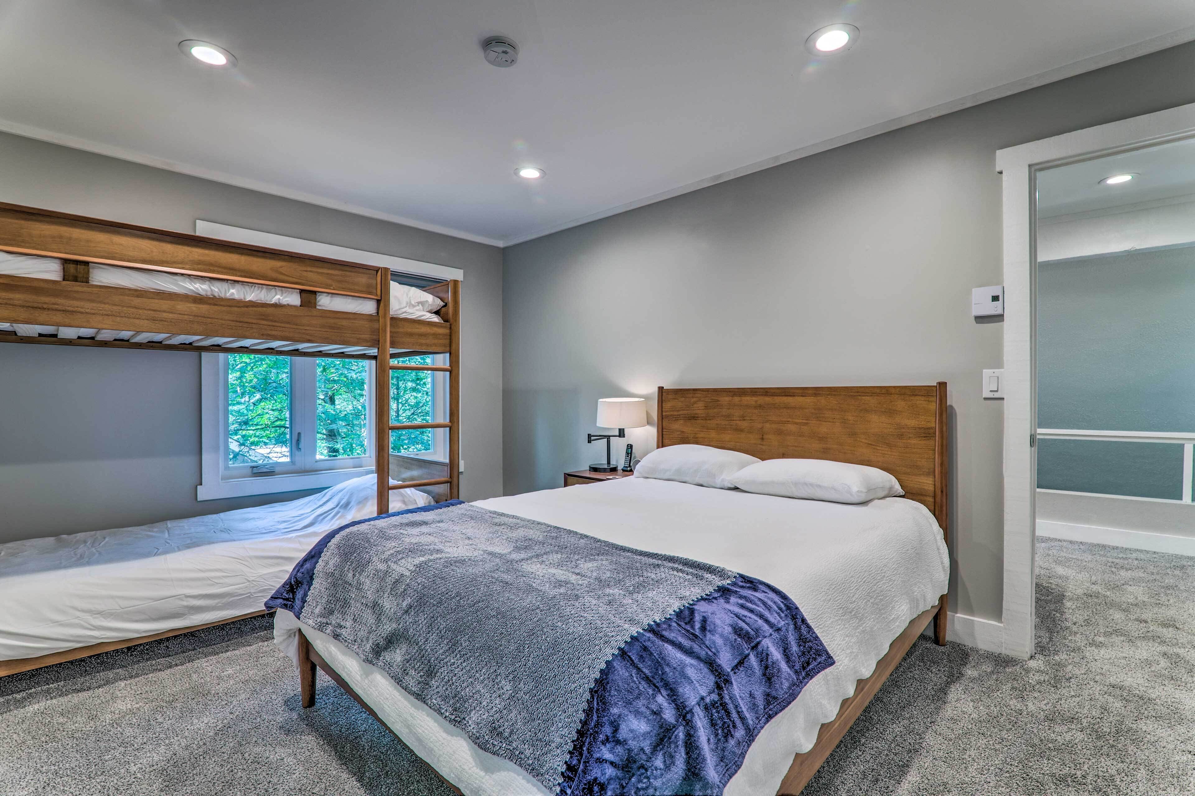 Quarto moderno com beliche, uma cama de solteiro e mesa de cabeceira com abajur.