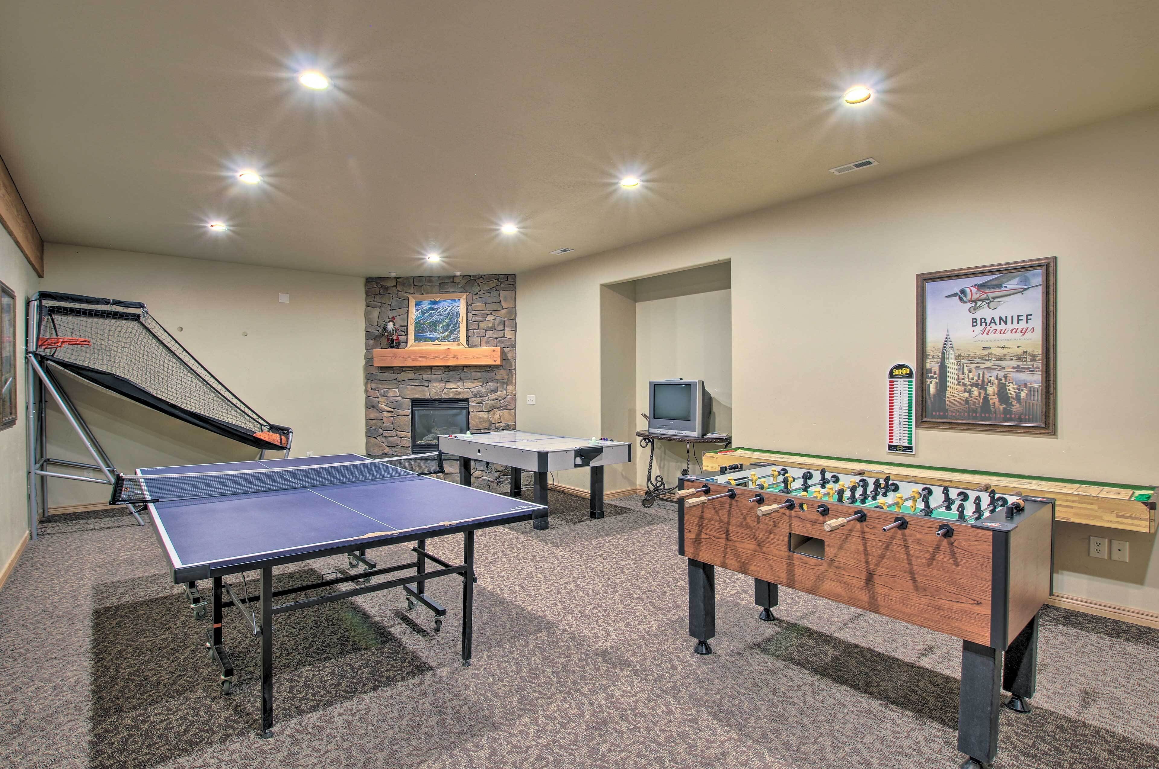 A recreational room with a ping pong table, foosball table, and a small television.