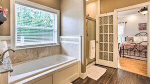 Une salle de bain avec une baignoire, une douche et une fenêtre avec des stores.