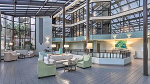A spacious lobby with multiple seating areas, a central water feature, and large windows offering views of the outdoors. - Coastal Orange Beach Condo: Resort + Beach Access! (Orange Beach)