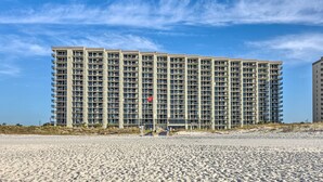 A high-rise hotel with multiple floors, a beach in the foreground, and a clear sky. - Coastal Orange Beach Condo: Resort + Beach Access! (Orange Beach)