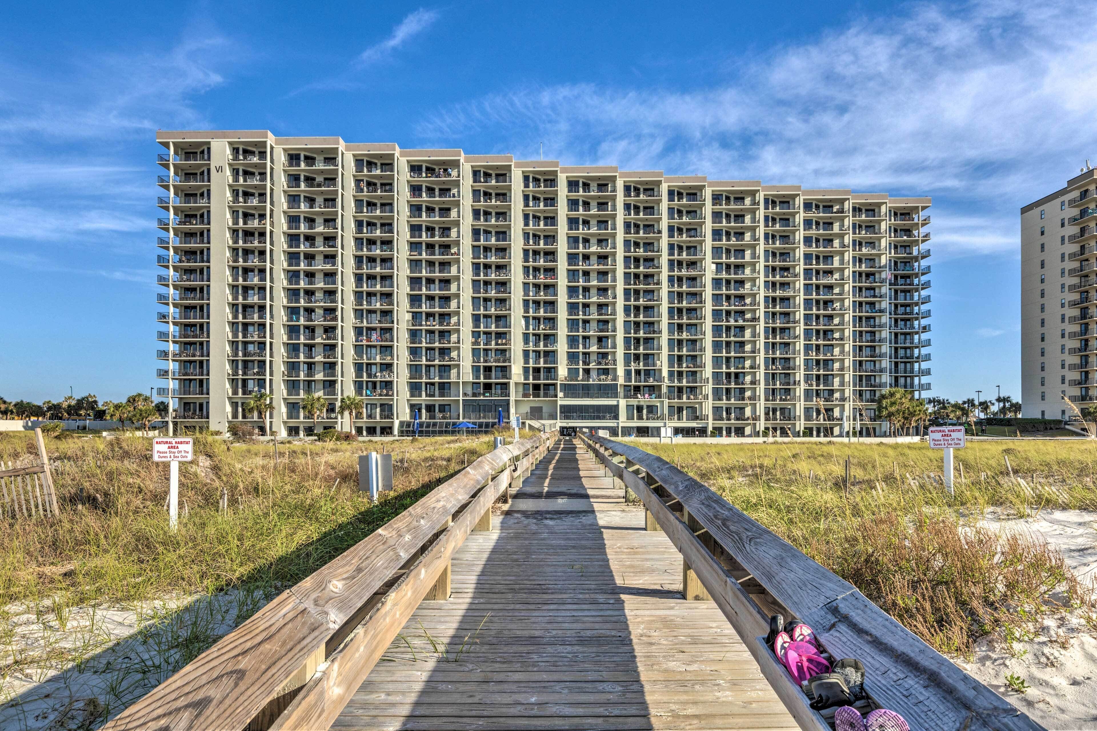 A multi-story hotel with a wooden boardwalk leading to the entrance.