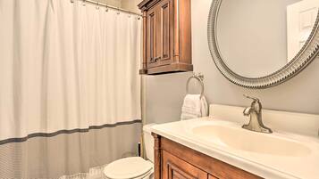 A bathroom with a toilet, a sink with a mirror, and a shower curtain.