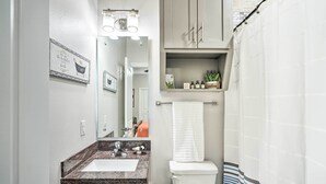 A bathroom with a sink, mirror, toilet, and towel rack.